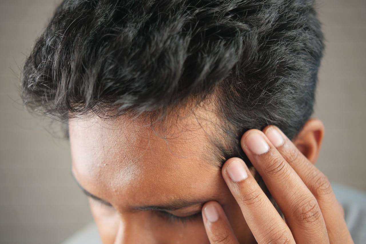 services-04 Close-up of a mans hand touching his head in contemplation. Neutral tones and soft lighting.